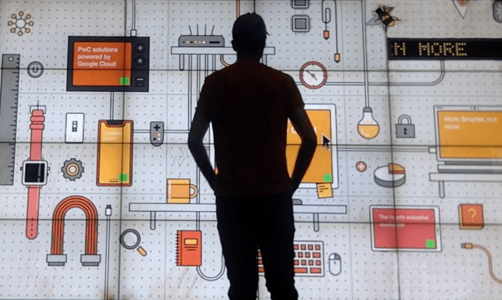 Man standing in front of giant screen with interactive items on it.